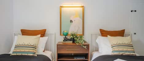 A hotel room with two beds, a nightstand with a globe and a plant, and a framed picture on the wall.