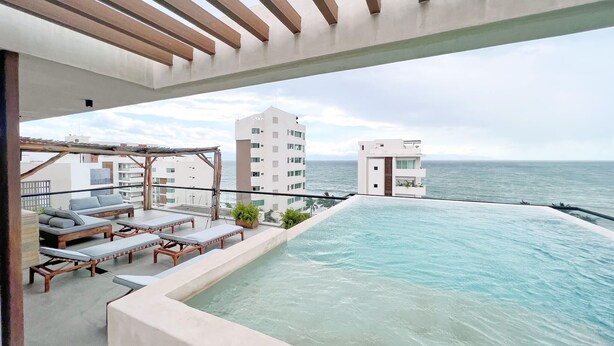 A rooftop infinity pool with lounge chairs, a pergola, and a view of the ocean. - Arenka: 2BR w Private Pool & Sunset Rooftop (Bucerías)