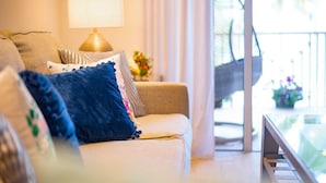 A cozy living room with a sofa, a lamp, and a view of a balcony.
