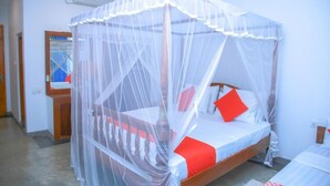 A single bed with a canopy, white bedding, and red pillows. - Surf Sea Breeze (Mirissa)