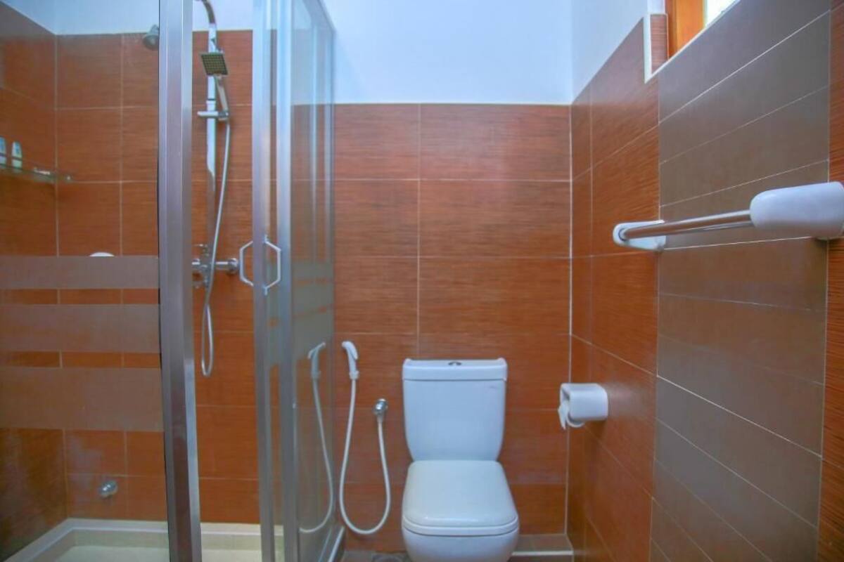 A bathroom with a glass shower enclosure, a white toilet, and a towel rack.