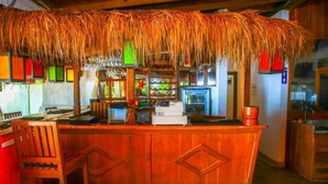 A wooden bar area with a thatched roof, a cash register, and various bar items. - Surf Sea Breeze (Mirissa)