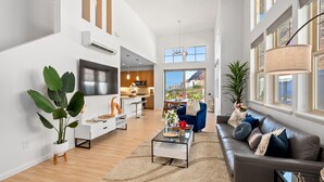 A spacious living room with a modern sofa, a coffee table, and a large window offering a view of the city.