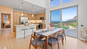 A modern kitchen with wooden cabinets, a central island, and a dining area with a table and chairs.