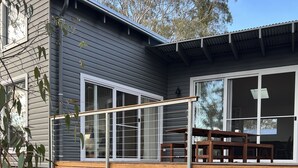 A wooden deck with a metal railing, a small arched entrance, and a table with chairs. - Beautiful Country Home.  5 min to Armidale, 10 min to University of New England. (Armidale)