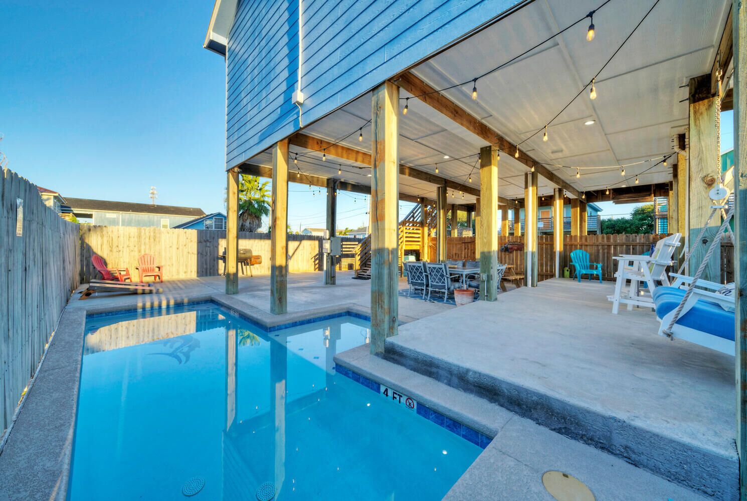 A backyard with a swimming pool, outdoor seating, and a covered patio area.