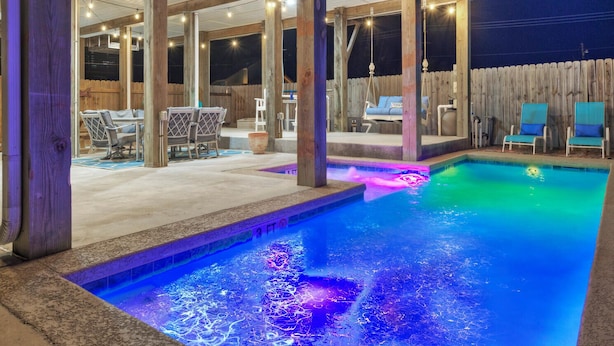 En udendørs swimmingpool med træterrasse og liggestole.