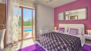 A bedroom with a large bed, a sliding glass door to a pool, a chandelier, and a mirror on the wall. - Gorgeous home in Pula (Pula)