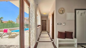 A hallway with a pool view, a bench, a clock, and a door. - Gorgeous home in Pula (Pula)