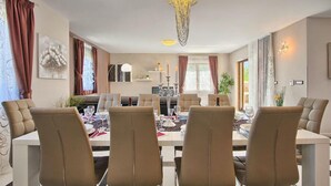 A dining area with a chandelier, cushioned chairs, and a table set for four. - Gorgeous home in Pula (Pula)