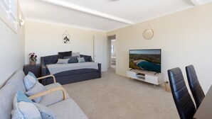 Une chambre à coucher moderne avec un lit, une télévision, un canapé et un fauteuil.