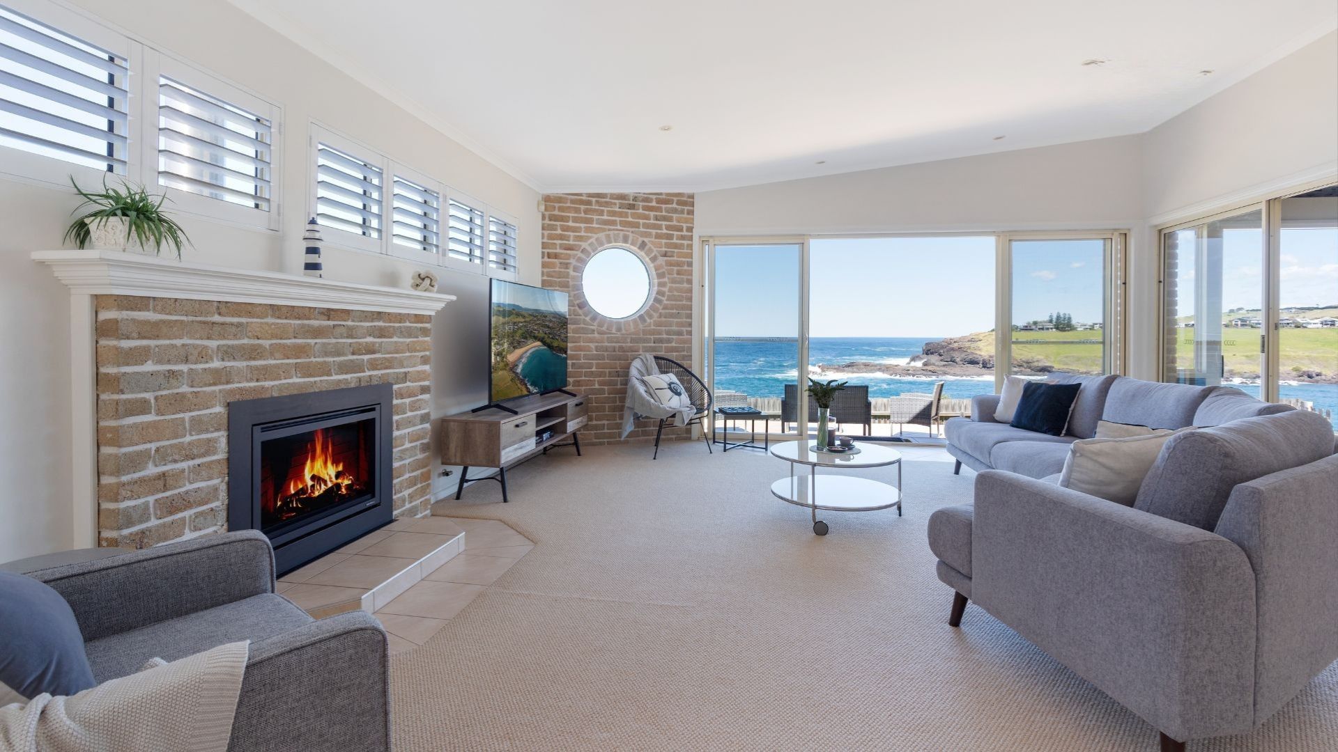 Un salón amplio con chimenea, televisor y vistas al océano.