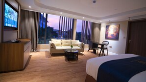 Una habitación de hotel moderna con una cama grande, un sofá, una mesa de comedor y un televisor.