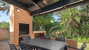 An outdoor patio with a table and chairs, a built-in grill, and lush tropical vegetation. - San Lameer Villa 2841 (Southbroom)
