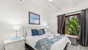 A bedroom with a bed, nightstands, a window with curtains, a ceiling fan, and a wall-mounted picture. - San Lameer Villa 2841 (Southbroom)