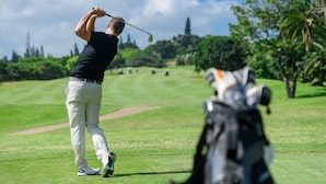 A golf course with a golfer in mid-swing, a golf bag, and a clear sky. - San Lameer Villa 2841 (Southbroom)