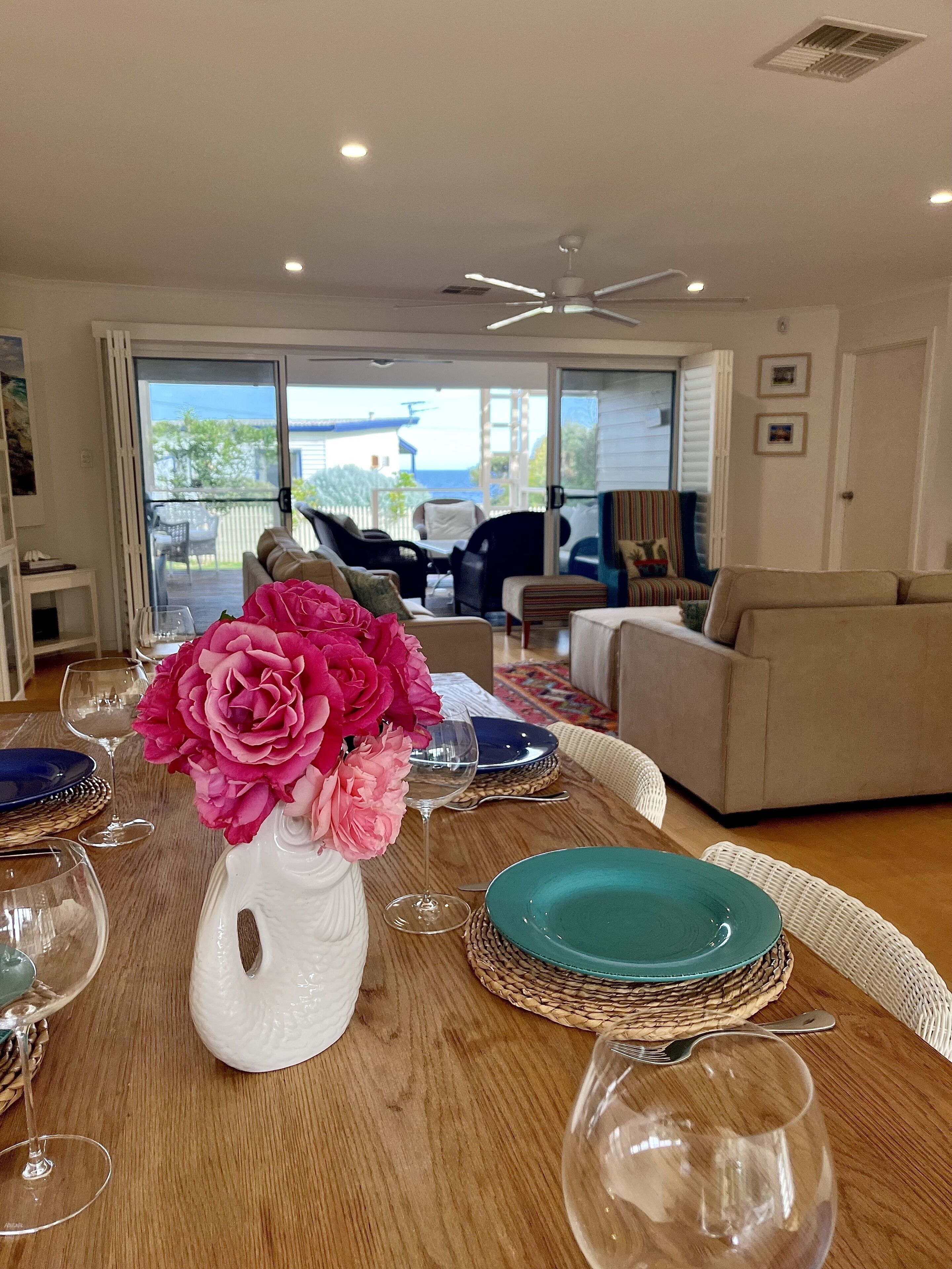 A dining table set with plates, glasses, and a vase of flowers.
