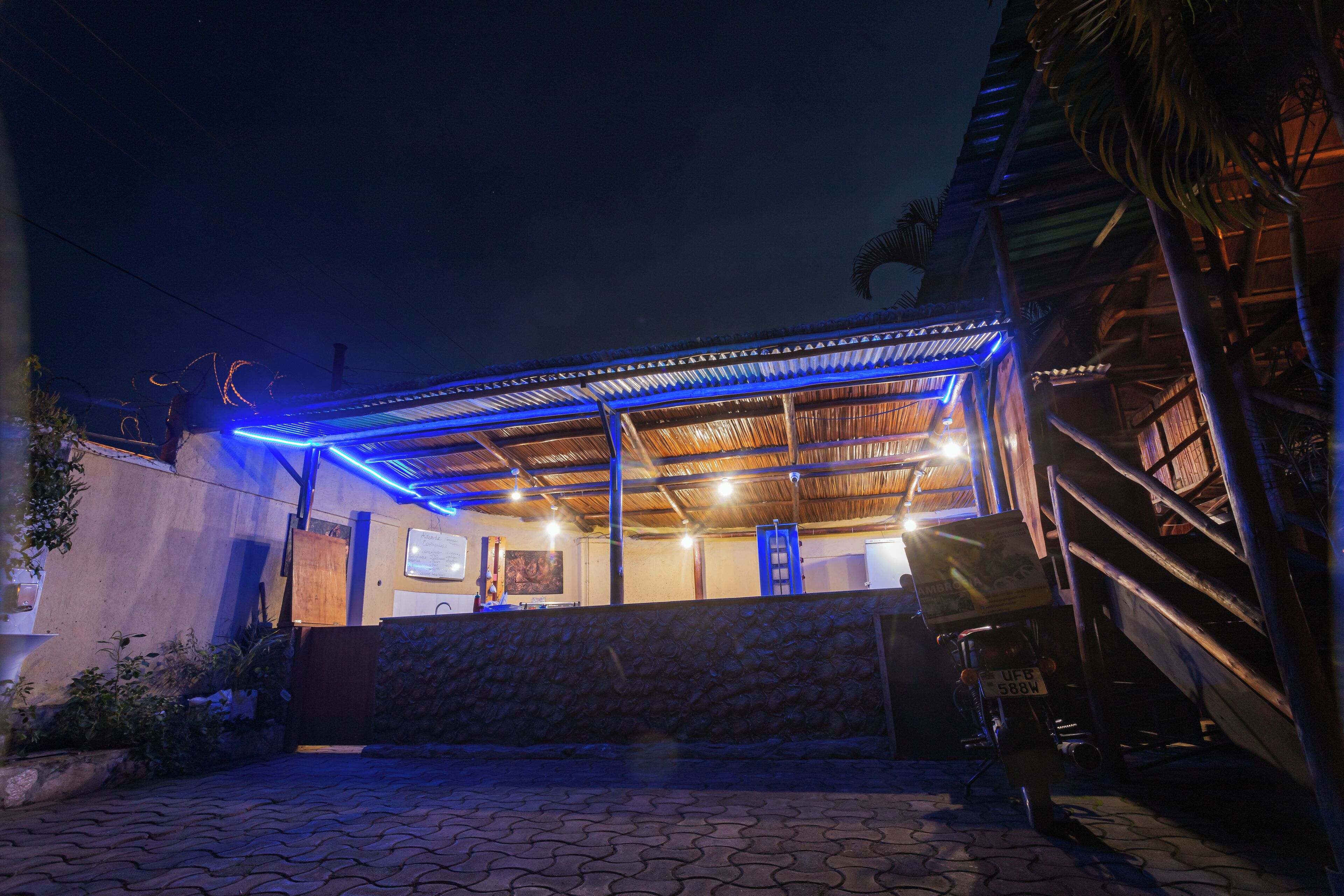 A building with a covered outdoor area, a staircase, and a vehicle parked outside.
