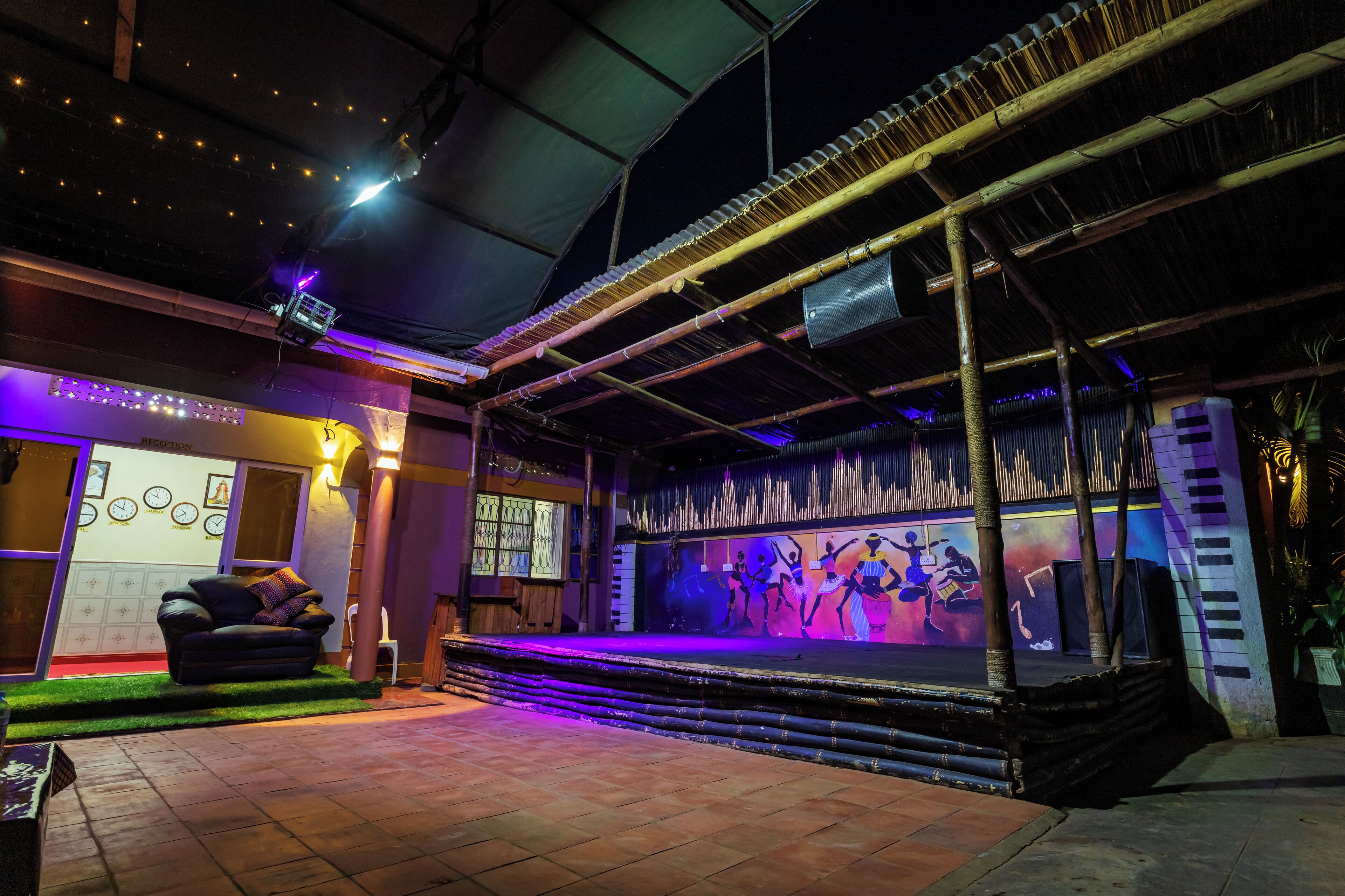 An outdoor stage with a performance area, a reception desk, and a seating area with a sofa.