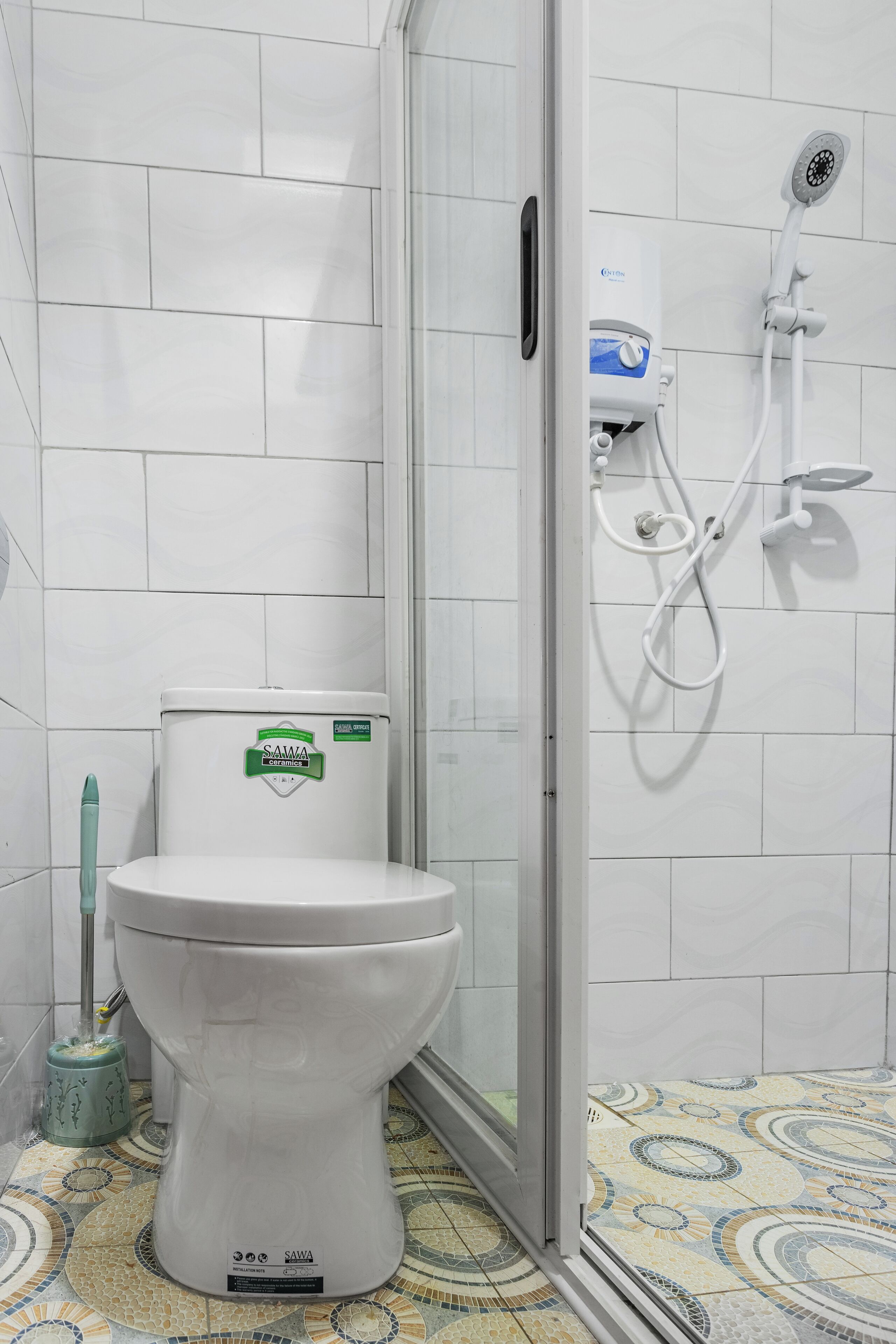 A bathroom with a toilet, a shower, and a tiled floor.