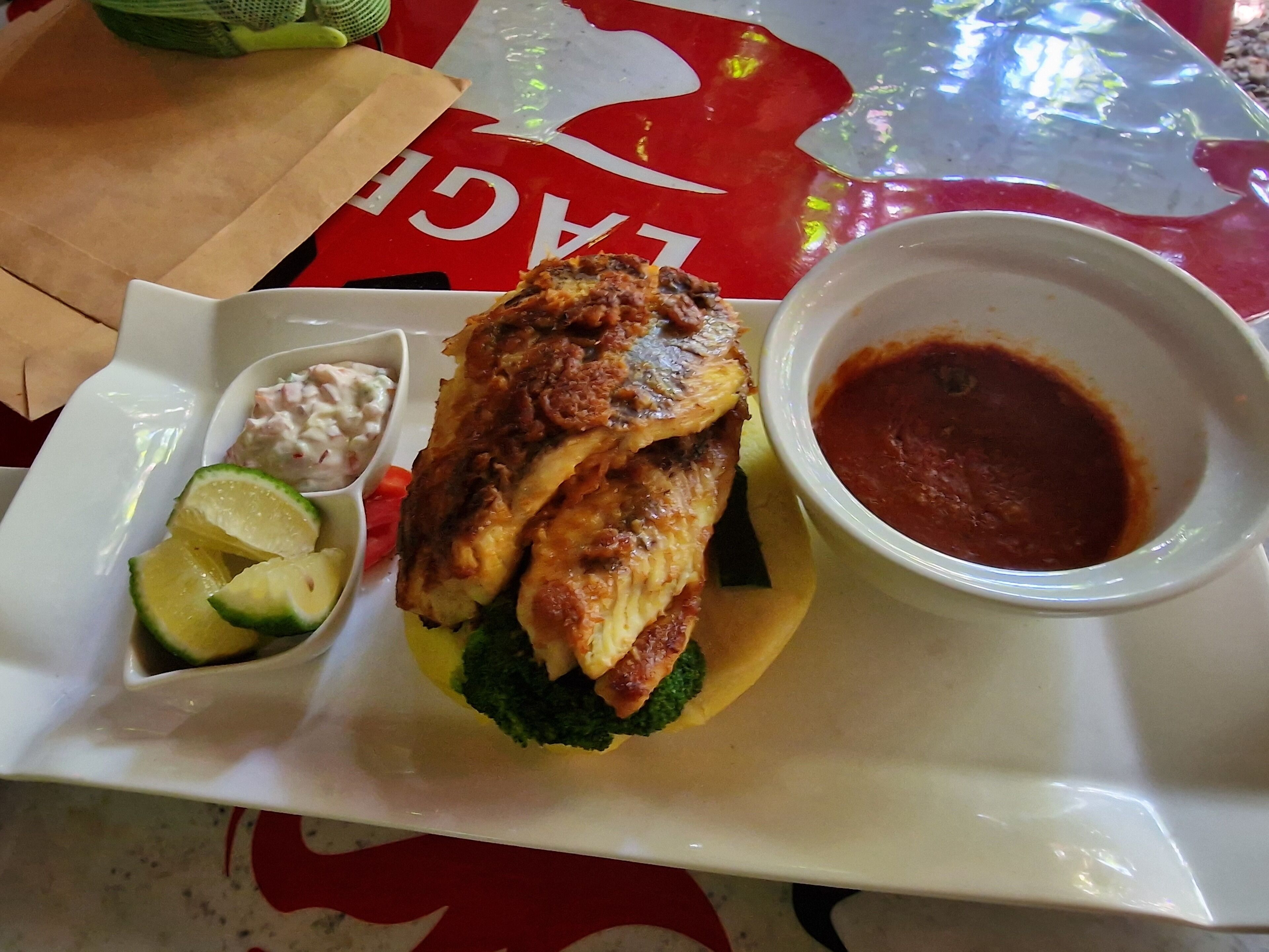 A meal consisting of a sandwich with a side of sauce and a small bowl of salad.
