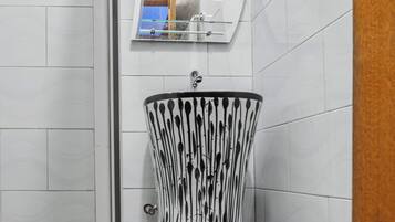 Un bagno con un lavandino moderno, uno specchio e un cestino.