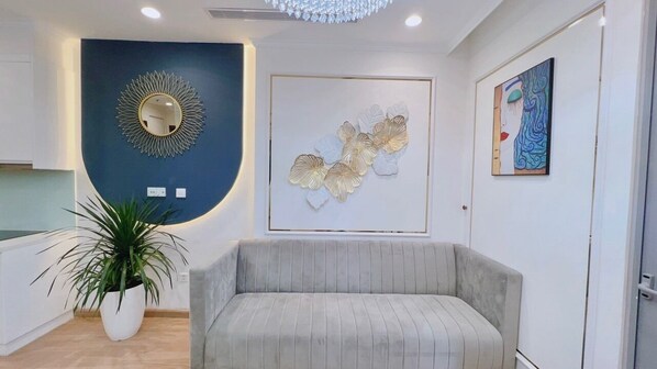 Un interior moderno con un sofá gris, una planta en maceta, un espejo montado en la pared y arte abstracto en la pared.