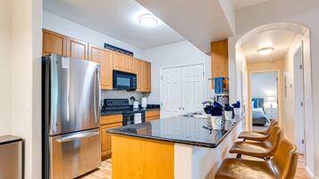 A modern kitchen with stainless steel appliances, wooden cabinets, and a central island with bar stools.