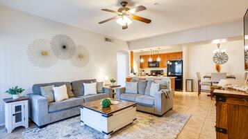 A modern living room with a grey sectional sofa, a wooden coffee table, and a ceiling fan.