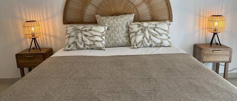 A bed with a large, curved headboard, two bedside tables with lamps, and patterned pillows.
