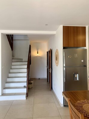 A modern kitchen with a stainless steel refrigerator, wooden cabinets, and a dining table.