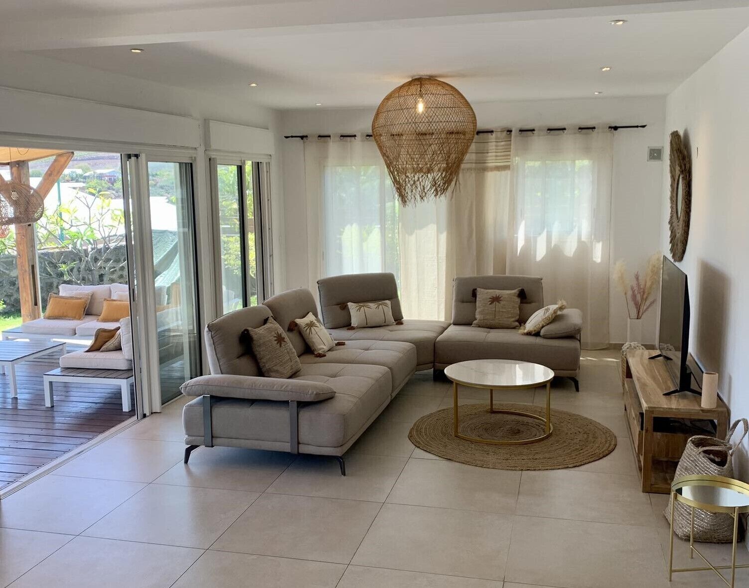 A modern living room with a sectional sofa, a round coffee table, and a TV on a wooden stand.