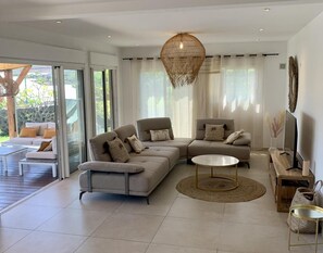 A modern living room with a sectional sofa, a round coffee table, and a TV on a wooden stand.
