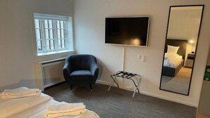 A hotel room with a bed, a chair, a TV, and a mirror. - Hotel Nørrevang (Vaeggerlose)