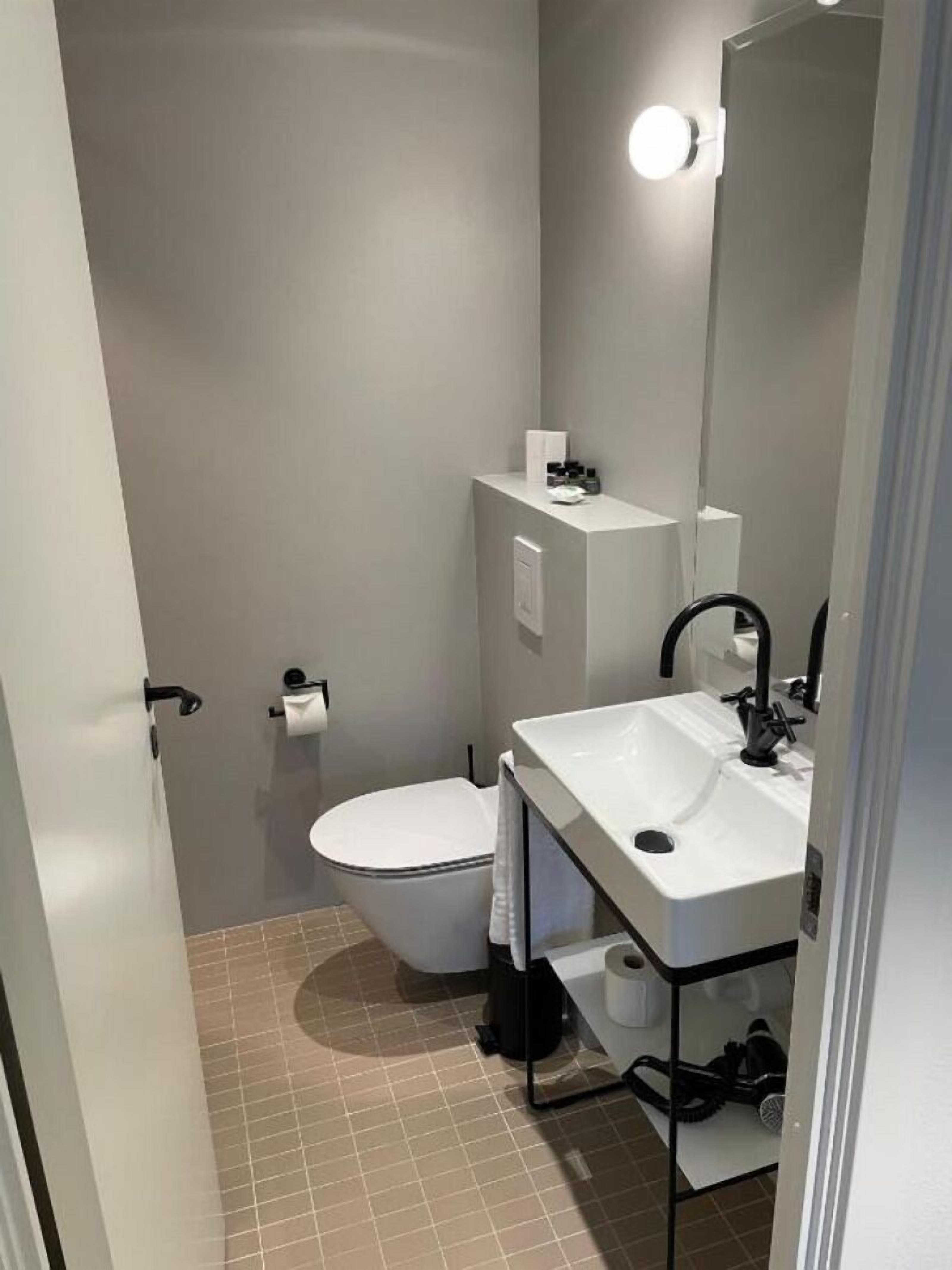 A compact bathroom with a toilet, a sink, and a mirror.