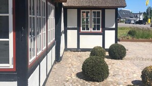 A traditional building with a thatched roof, white walls, and black timber framing. - Hotel Nørrevang (Vaeggerlose)