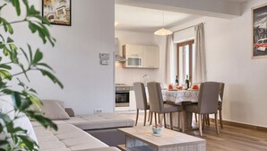 Un soggiorno moderno con un divano, un tavolo da pranzo imbandito per quattro persone e una cucina sullo sfondo.