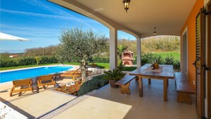 Un'area esterna coperta con piscina, mobili in legno e un forno a mattoni.