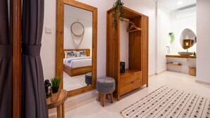 Une chambre à coucher moderne avec une armoire en bois, un miroir, une table de chevet agrémentée d’une plante et un tapis à motifs.
