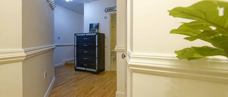 A hallway with wooden flooring, a black filing cabinet, and a door labeled "ABBEY".