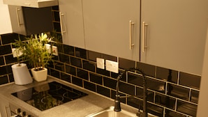 A compact kitchen with a built-in washing machine, a sink, and a stove. - White Tulip Central 3bedroom Duplex Loft (Liverpool)
