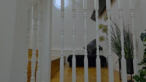 A staircase with white balusters, a wooden floor, and a black object on the landing. - White Tulip Central 3bedroom Duplex Loft (Liverpool)