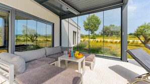A modern outdoor living area with a sofa, a table, and a chair, overlooking a scenic landscape. - Stunning home in Pula (Pula)