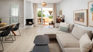 Una sala de estar moderna con un sofá, una mesa de comedor con sillas, una chimenea y vistas al exterior.