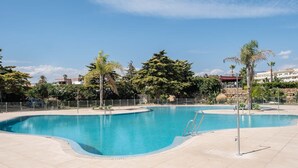 A large, clear swimming pool with a curved edge, surrounded by a tiled deck. - Chaparral Seafront by Alfresco Stays (Mijas Costa)