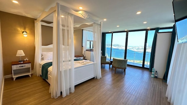 Une chambre à coucher avec un lit à baldaquin, une table de chevet, une chaise et une vue sur la mer.