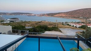 Une piscine sur le toit offrant une vue sur la mer et sur le paysage urbain au loin.