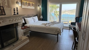 Une chambre avec un lit, une cheminée, une vue sur la mer et un balcon.