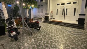 Een overdekt buitengebied met een scooter, een betegelde vloer en een gebouwdeur met dubbele deuren.