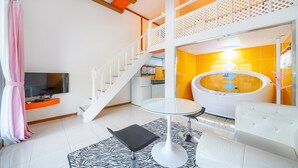 Una sala de estar moderna con una escalera, una mesa con cubierta de vidrio, un tapete estampado con motivos de cebra y un sofá blanco.